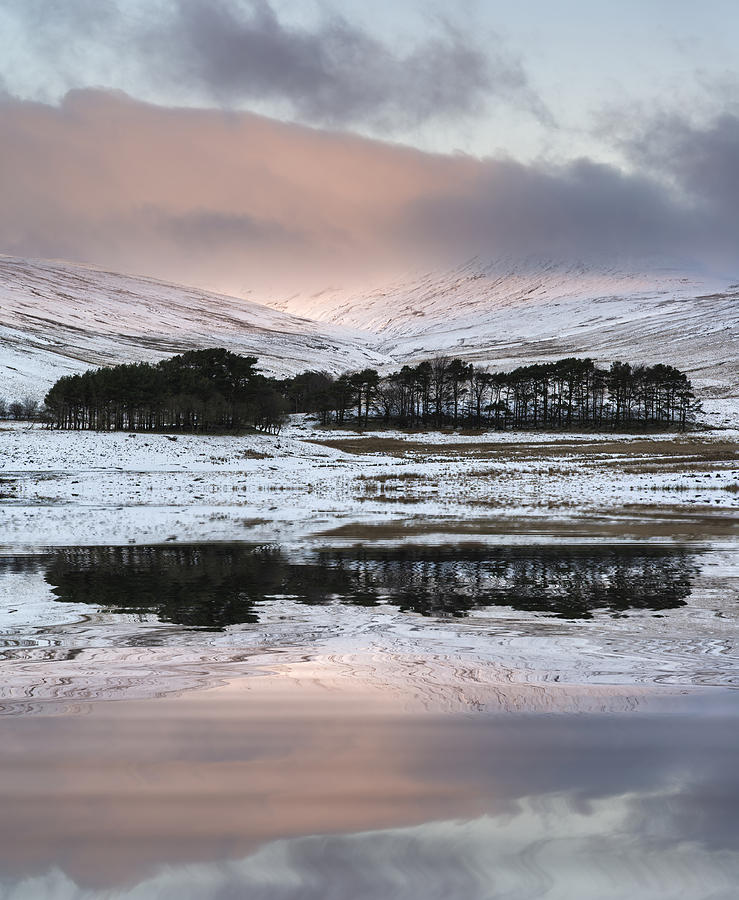 Winter Photograph - Stunning pink sunrise over mountain ladnscape refleted in calm l by Matthew Gibson