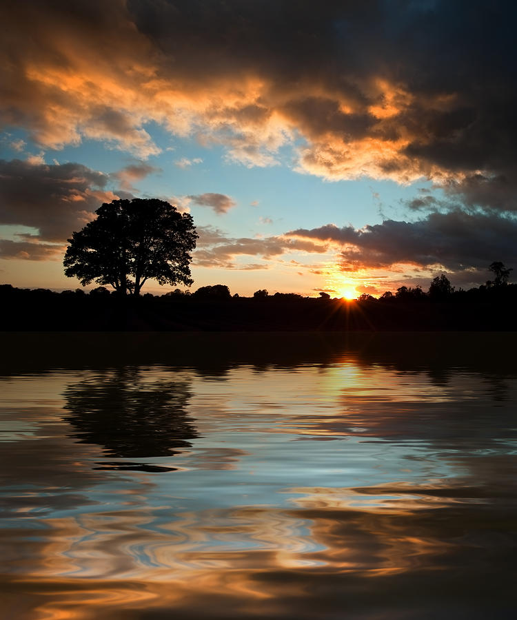 Sunset Photograph - Stunning sunset silhouette reflected in calm lake water by Matthew Gibson