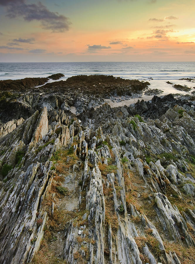 Sunset Photograph - Stunning vibrant rock formation against ocean and beautiful suns by Matthew Gibson