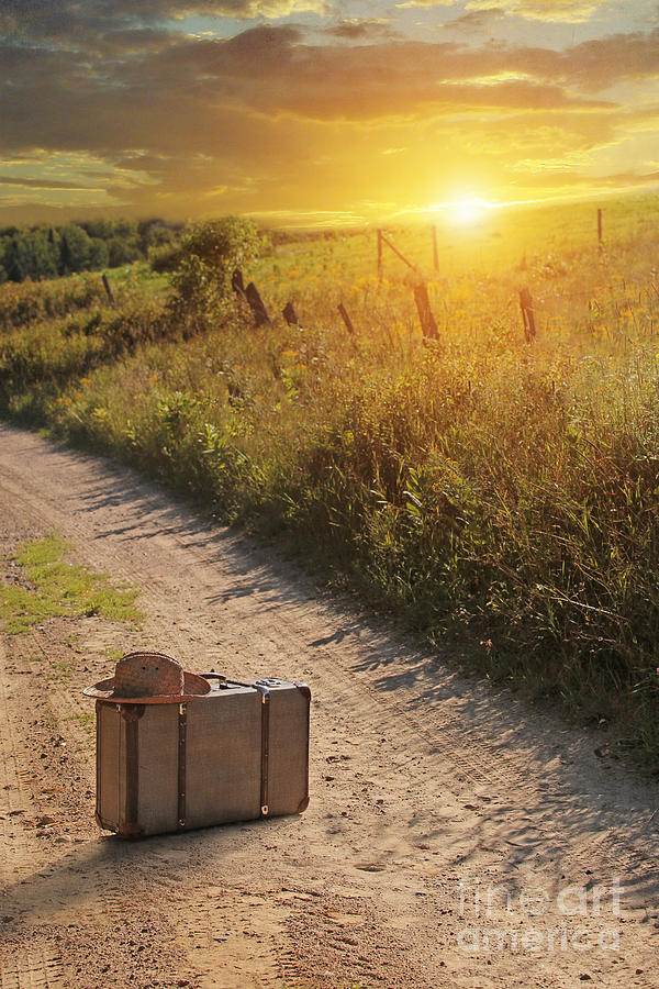 Suitcase with hat on road at sunset Photograph by Sandra Cunningham