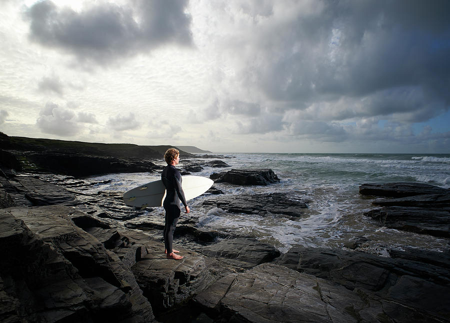 Surfer Standing On Rocks And Looking Photograph by Dougal Waters