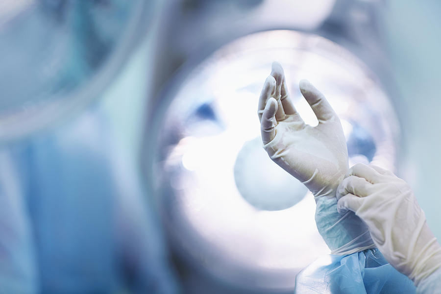 Surgeon adjusting glove in operating room Photograph by Shannon Fagan