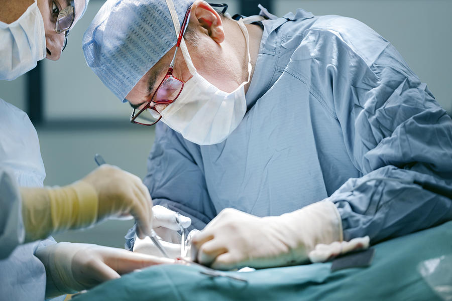 Surgeon performing surgery in full medical gear Photograph by Muratkoc