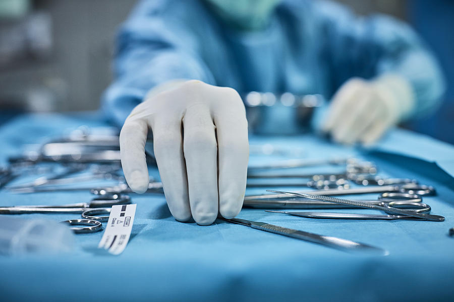 Surgeon picking up surgical tool from tray Photograph by Morsa Images