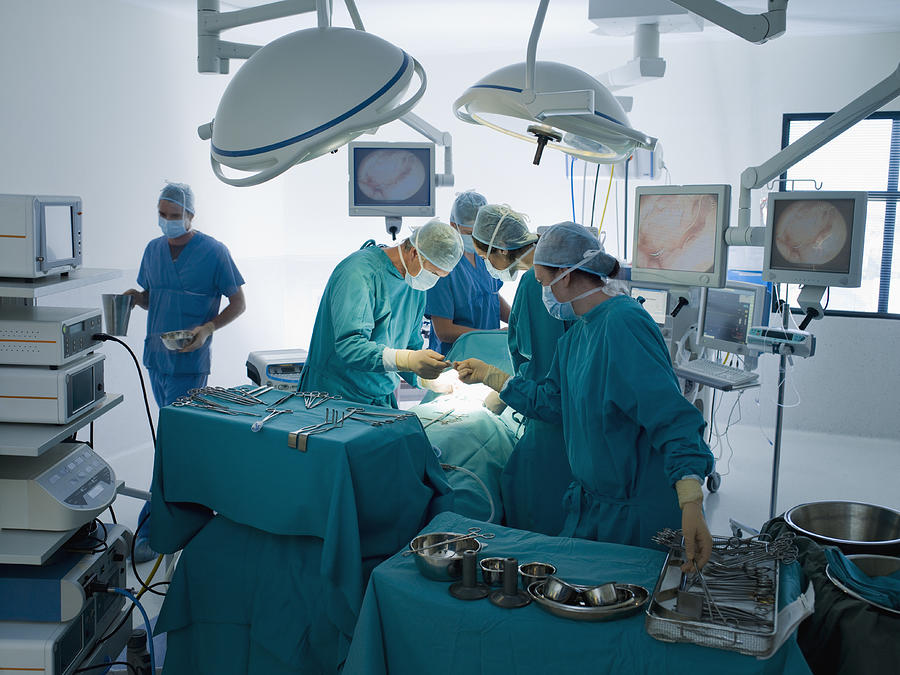 Surgeons performing operation in operating room Photograph by Chris Ryan