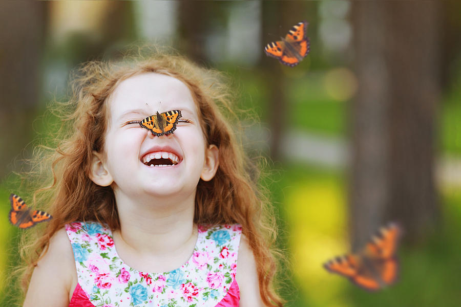Surprised curly girl with a butterfly on his nose. Photograph by Ulkas