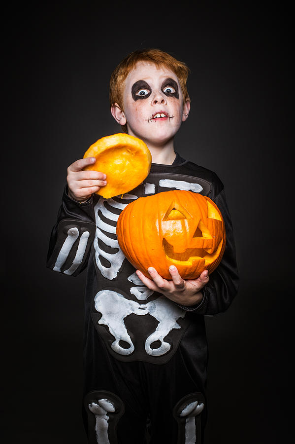 Surprised Red Haired Child In Skeleton Costume Holding A Orange Pumpkin. Halloween Photograph