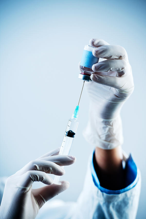 Syringe into flu vaccine. Photograph by Skynesher