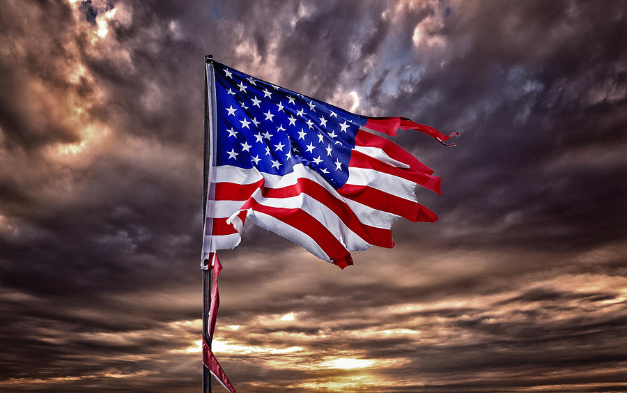 Tattered American flag flapping in ominous sky Photograph by Tirc83