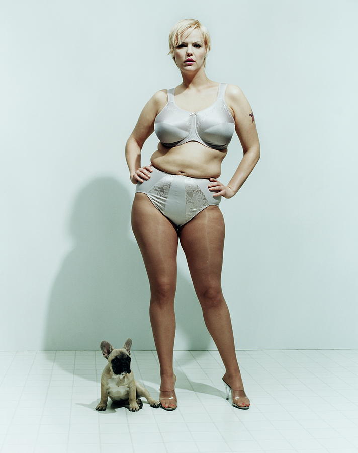 Tattooed woman in underwear standing beside dog, portrait Photograph by Matthias Clamer