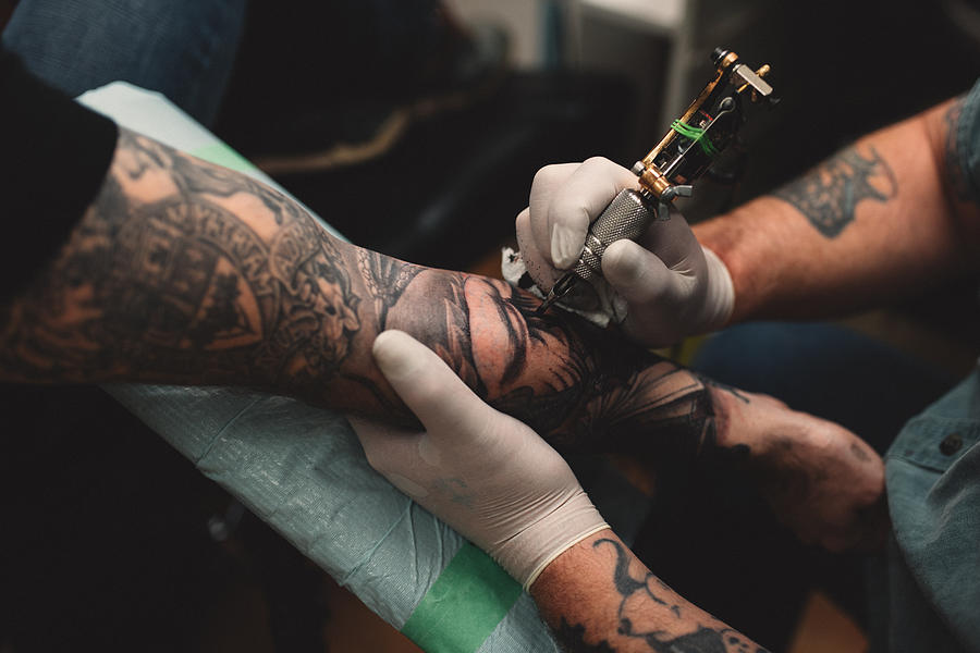 Tattooist tattooing young mans arm, close-up Photograph by Kymberlie Dozois Photography