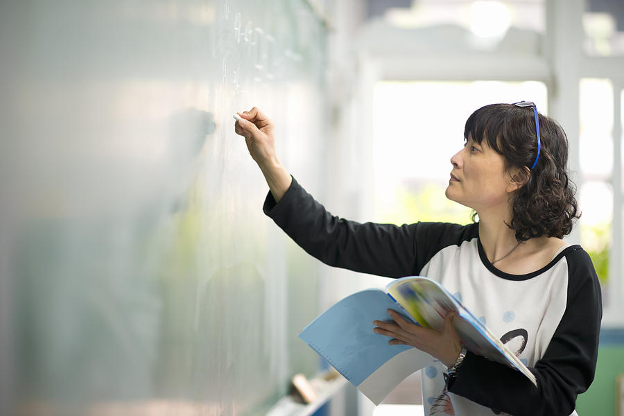 Teacher writing on chalkboard Photograph by Leren Lu