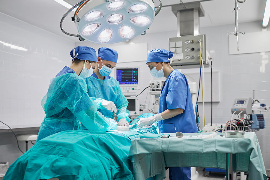 Team of surgeons in operating room at a hospital. Photograph by Tempura