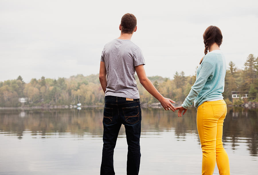 Teen couple holding hands by a lake Photograph by Ron Levine