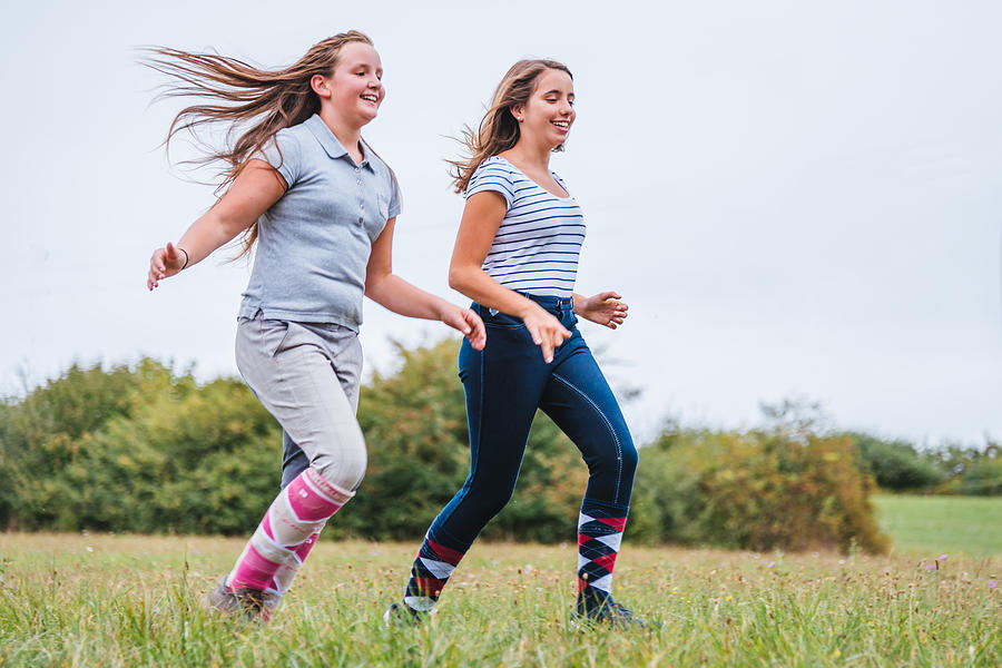 Teen girls running together on summer meadow Photograph by Mlenny