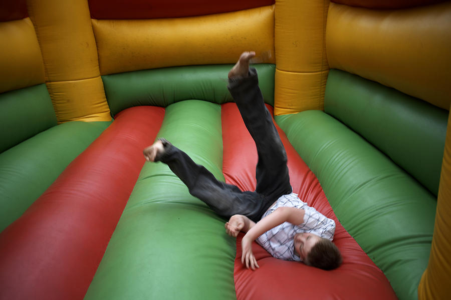 Teenage boy (13-14) jumping in bouncy castle Photograph by Simon Bottomley