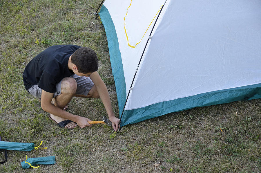 Teenage boy setting up a tent, France Photograph by Sami Sarkis