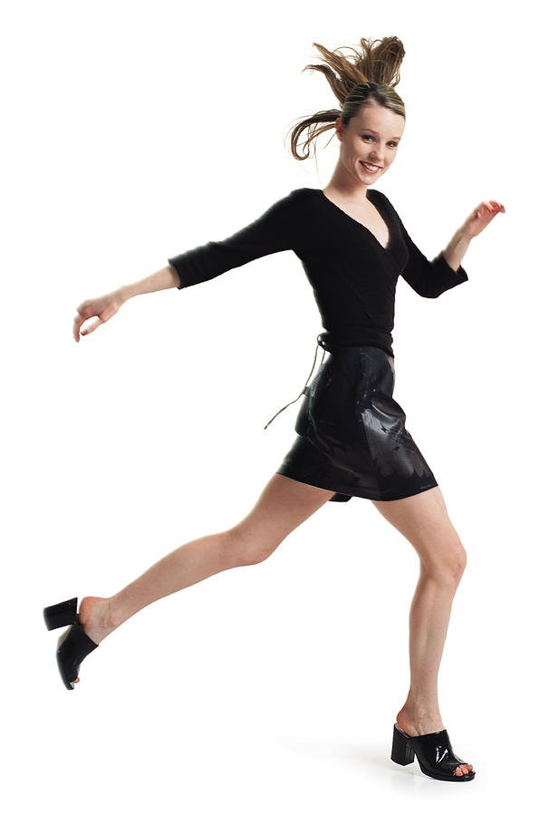 Teenage Female In A Black Skirt And Blouse Jumps And Steps Forward In Long Strides Turns And Smiles Photograph by Photodisc