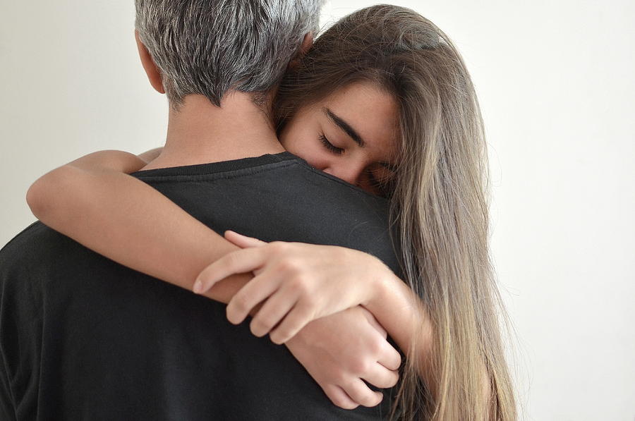 Teenage girl hugging her father Photograph by Ceciangiocchi