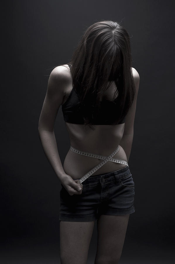 Teenage girl measuring her waist Photograph by PhotoStock-Israel