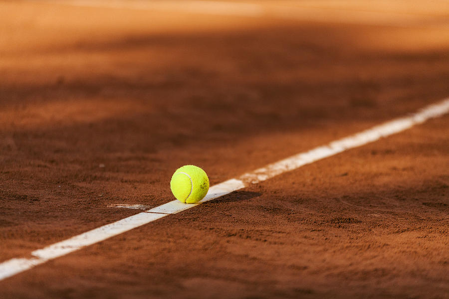Tennis ball hitting the line on clay court Photograph by Westend61