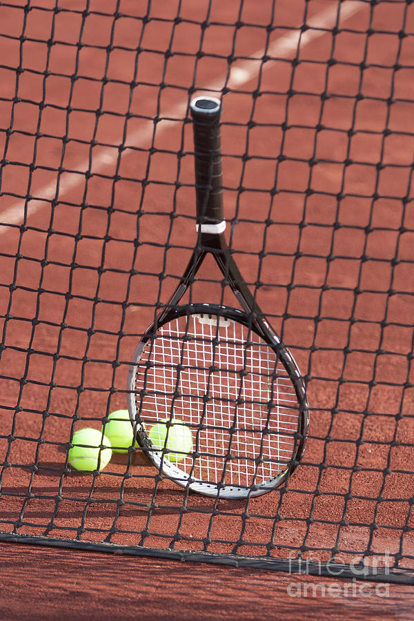 Tennis racket and balls against a net. Photograph by Don Landwehrle