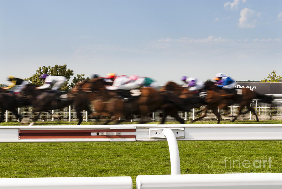 The blur of racehorses racing by the rails on a race track  Photograph by Peter Noyce