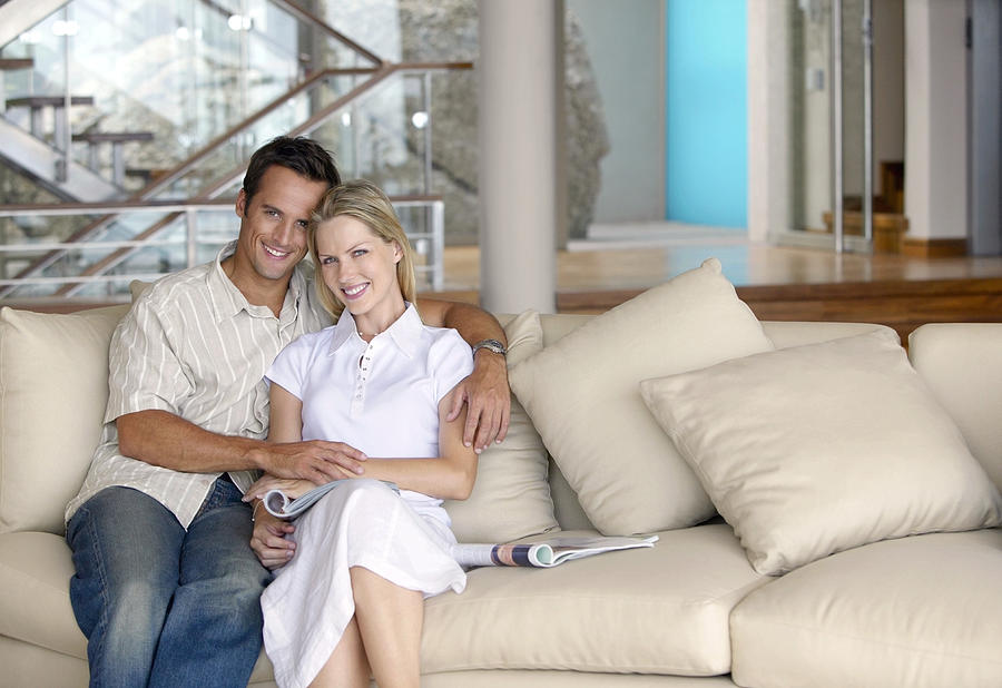 Thirty something Couple Sitting Side by Side on a Sofa in an Apartment Photograph by Flying Colours Ltd