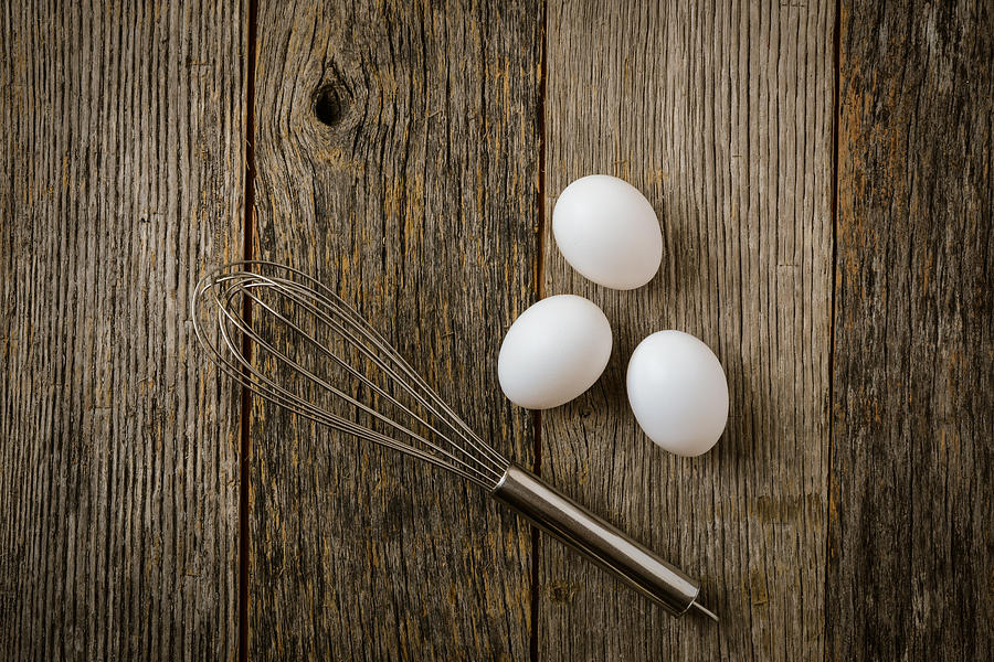 Three Eggs and Whisk or Egg Beater on Rustic Wood Background Photograph by Brandon Bourdages