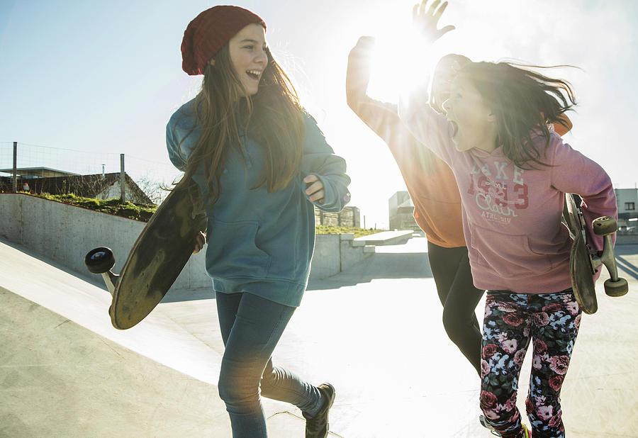 Three girls running in skatepark Photograph by Westend61