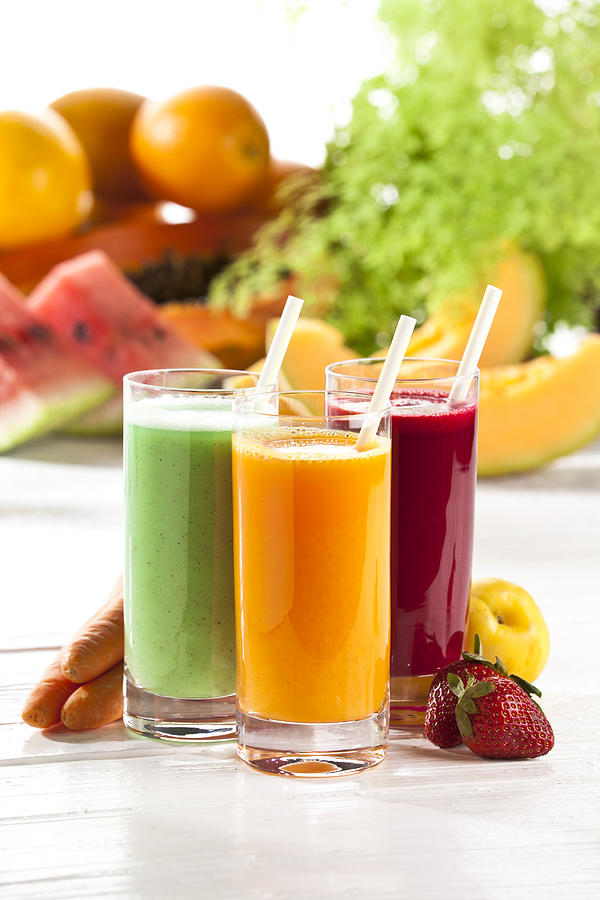 Three glasses of fruit juice with fruits in the background Photograph by Fcafotodigital