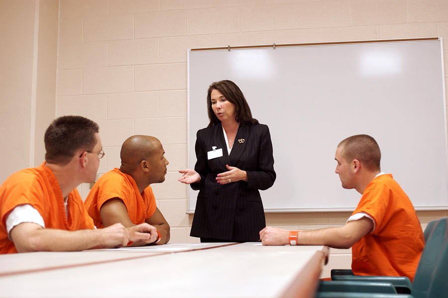 Three inmates listen to a woman discuss options and privileges that they might earn while serving time in prison. Photograph by Thinkstock
