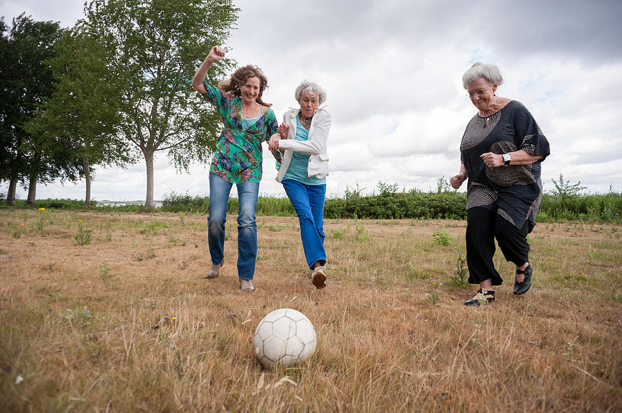 Three women playing soccer outdoors Photograph by Lucy Lambriex