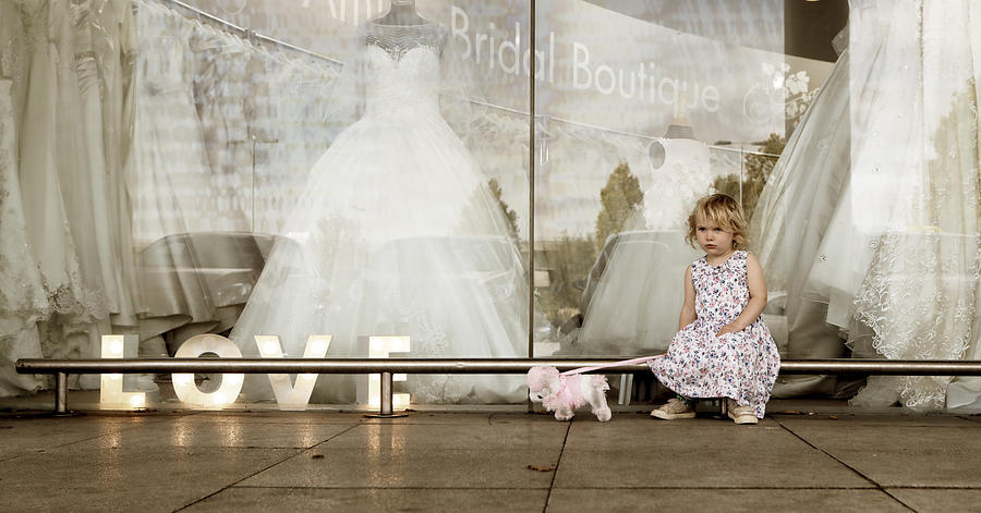 Toddler girl with toy dog sat outside bridal shop window Photograph by Peter Cade