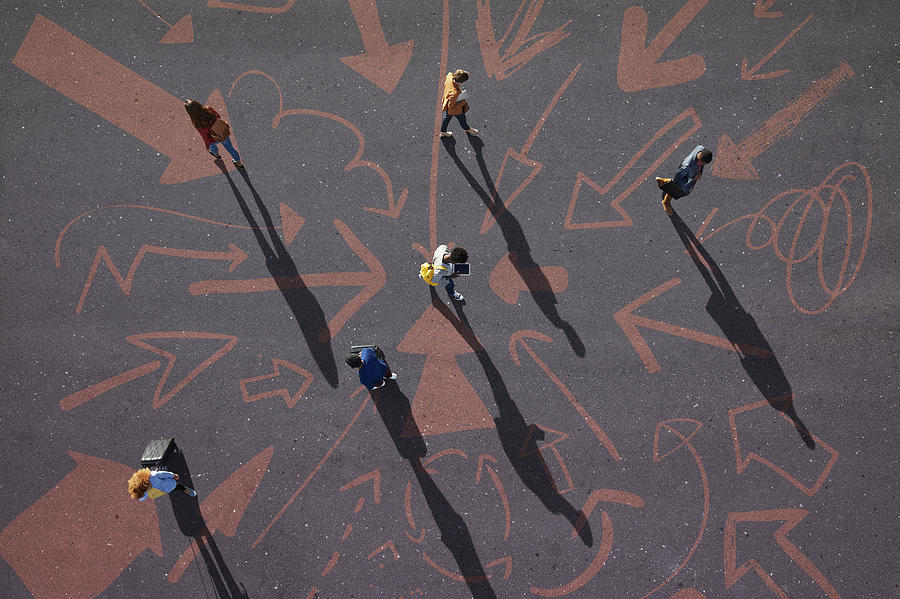 Top view of people walking around on painted asphalt with arrows Photograph by Klaus Vedfelt