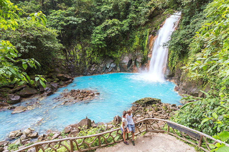 Tourist couple looking at Rio Celeste waterfall Photograph by Matteo Colombo