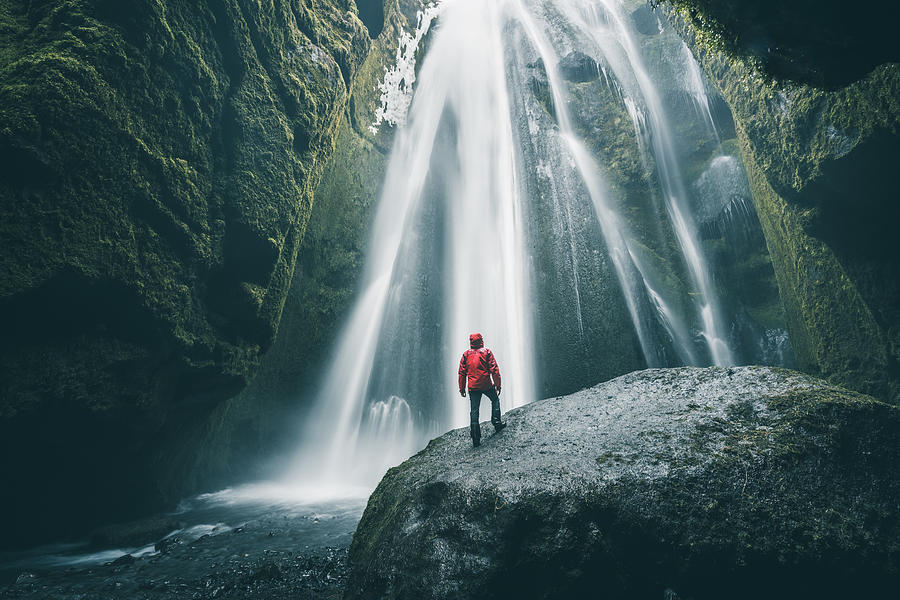 Tourist on a rock admiring Gljufrabui waterfall, Iceland Photograph by © Marco Bottigelli