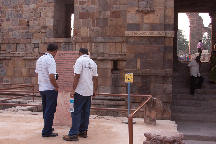 Tourists reading a sign inside the Qutub Minar complex in New Delhi in India Photograph by Ashish Agarwal