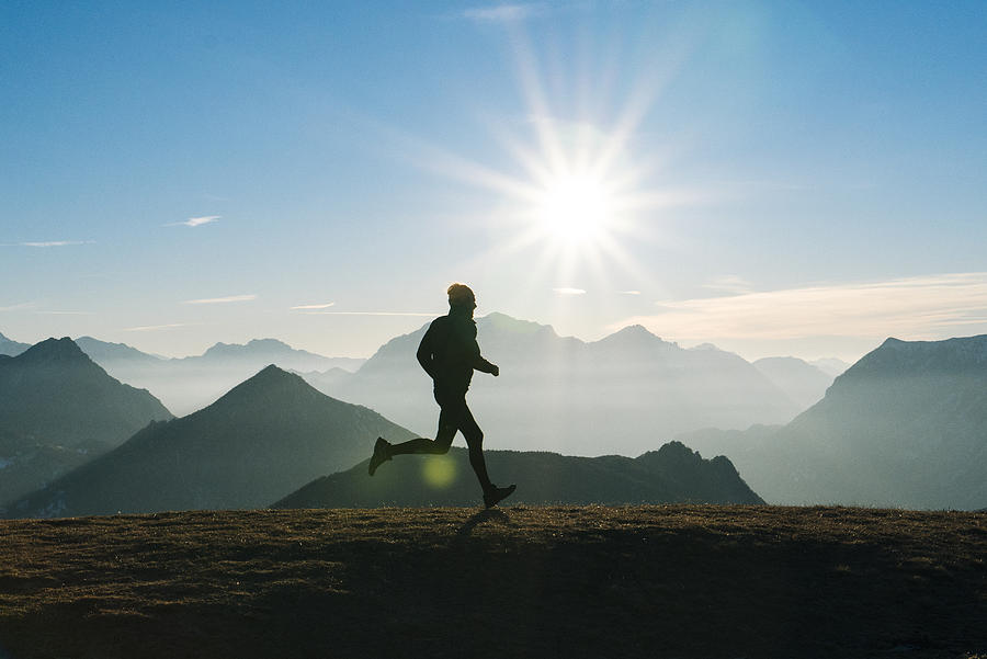 Trail runner strides across mountain summit, sunrise Photograph by Ascent/PKS Media Inc.