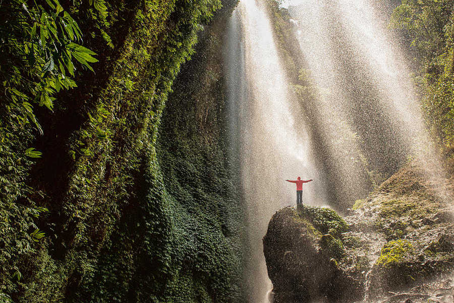 Traveler standing on the rock in the tropical rainforest at Madakaripura Waterfall , east java , indonesia Photograph by Photo by Supoj Buranaprapapong