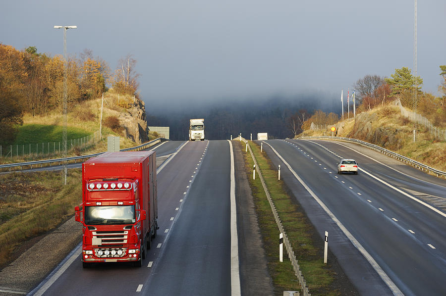 Trucks Driving Through A Misty Mountain Pass Photograph by Christian Lagereek