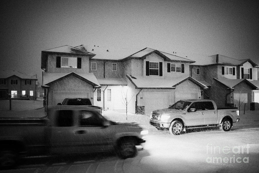 Winter Photograph - trucks driving through street with snow falling in residential neighborhood in Saskatoon Saskatchewa by Joe Fox