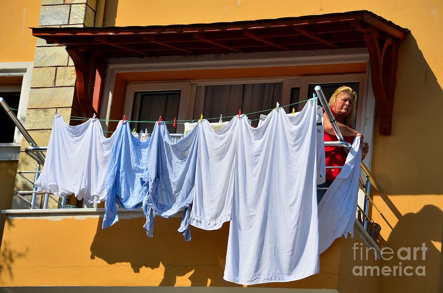 Turkish woman hangs laundry to dry from balcony Photograph by Imran Ahmed