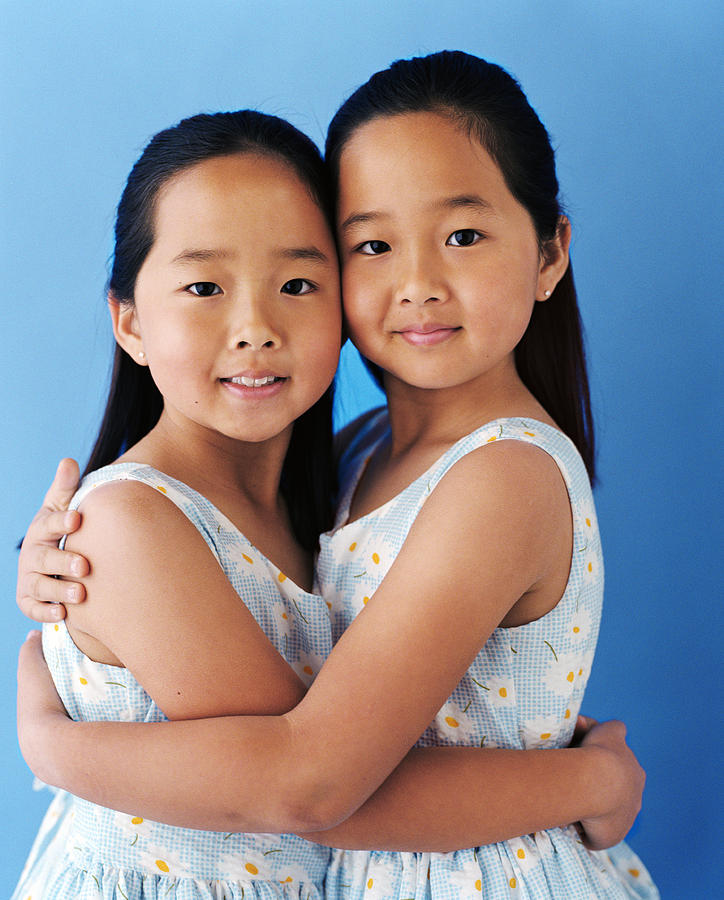 Twin girls (5-7) wearing dresses with daisy print Photograph by Ray Kachatorian