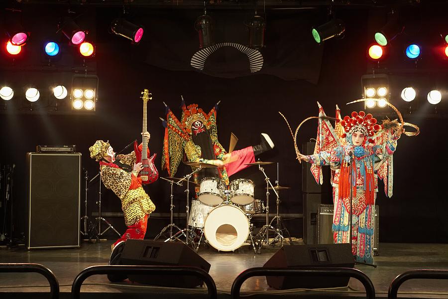 Two actors and an actress dressed as traditional Beijing Opera characters play rock and roll together on stage. Photograph by Blue Jean Images