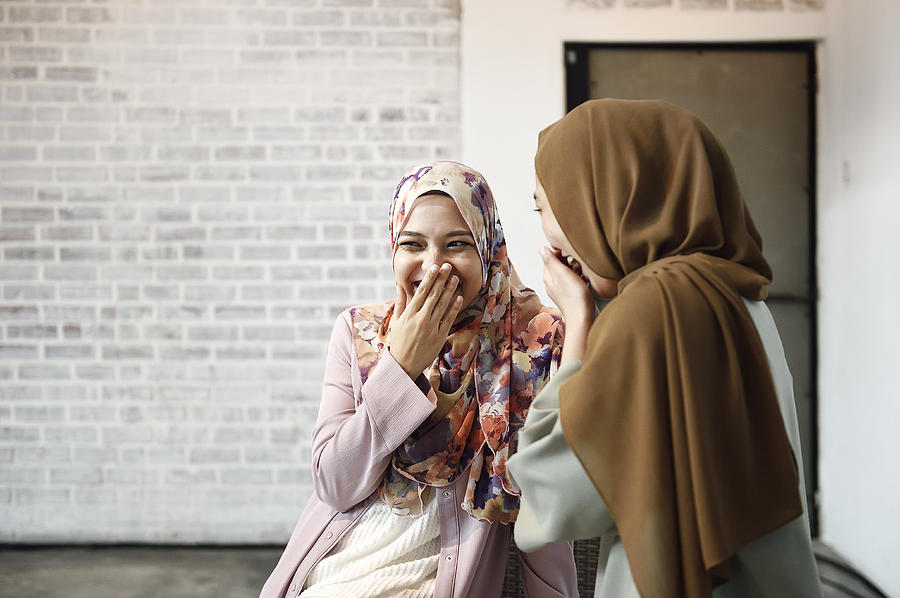 Two beautiful Malay ladies chatting indoors Photograph by Carlina Teteris