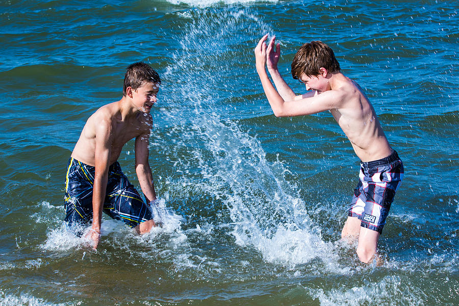 Two boys splashing water at each other in the ocean Photograph by Dfmjr1