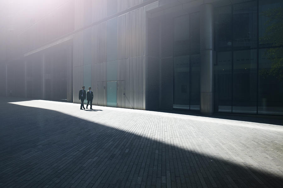 Two businessmen walking through the city. Photograph by Ezra Bailey