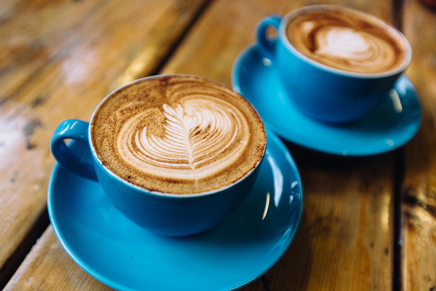 Two cups of coffee in blue cups on a wooden table close up Photograph by Alexander Spatari