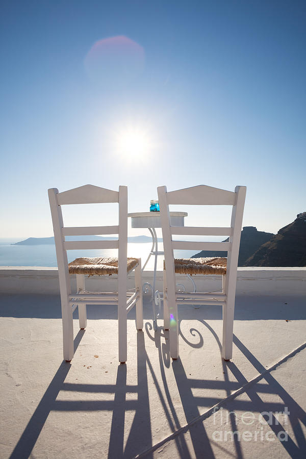 Two empty chairs overlooking blue mediterranean sea in Santorini Photograph by Matteo Colombo